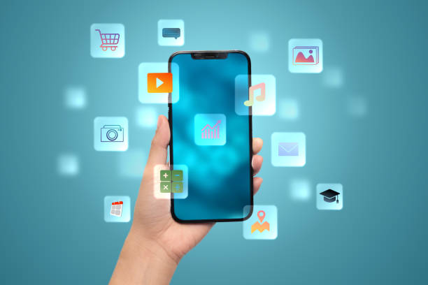 istock A hand holding a cell phone with a blue background and many icons on the screen. 2201599431
