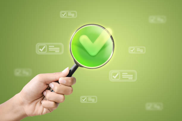 A hand holding a magnifying glass with a green checkmark, symbolizing quality assurance and successful verification.