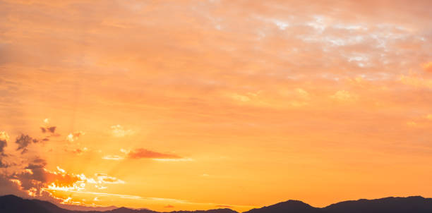 Dramatic sunset sky clouds over mountain hill countryside with colorful fluffy clouds orange, yellow sunlight in the evening, Horizon sky landscape backgrounds