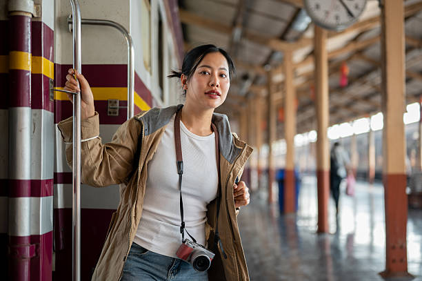 istock Asian woman carrying a camera is looking around while coming down from the carriage at train station 2201604523