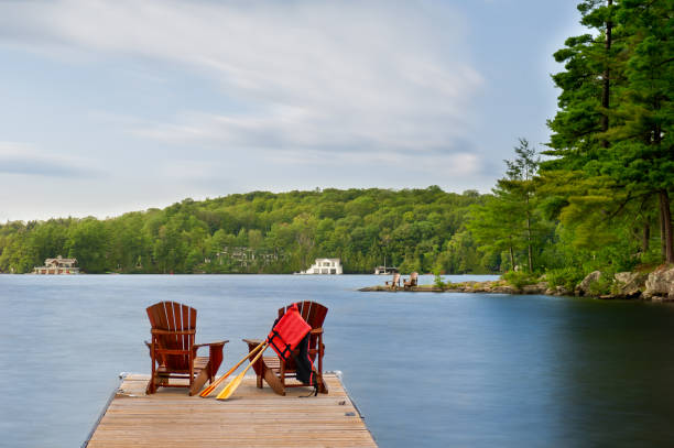 istock Adirondack chairs on a Muskoka dock with paddles and a life jacket. 2201609395