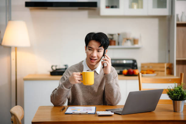 istock Young Asian man with sitting working on laptops and tablets in a cozy workspace. Perfect for education, innovation, and remote work themes 2201611553