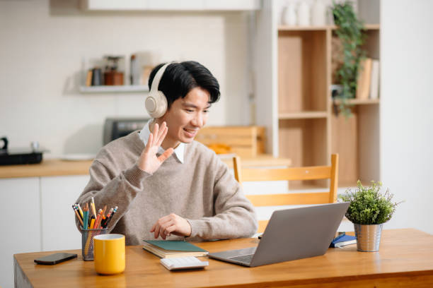 istock Young Asian man with sitting working on laptops and tablets in a cozy workspace. Perfect for education, innovation, and remote work themes 2201611593