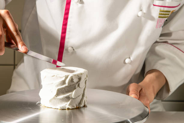 istock chef decorating cake with cream, close-up of hands 2201612178