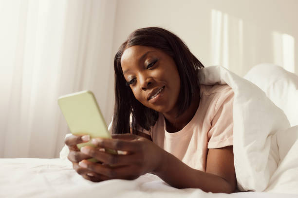 istock Happy black woman using smart phone during morning in a bed. 2201623127