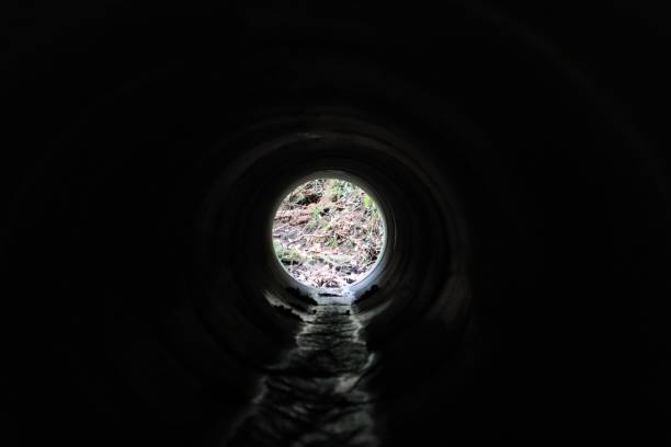istock View through a round concrete tunnel carrying a stream beneath a road 2201628329