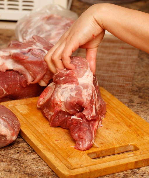 istock A person is cutting meat on a wooden cutting board 2201628395