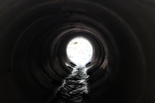 istock View through a round concrete tunnel carrying a stream beneath a road 2201628612