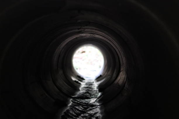istock View through a round concrete tunnel carrying a stream beneath a road 2201628618