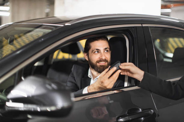 istock Businessman receives car keys while sitting inside rental vehicle 2201629069