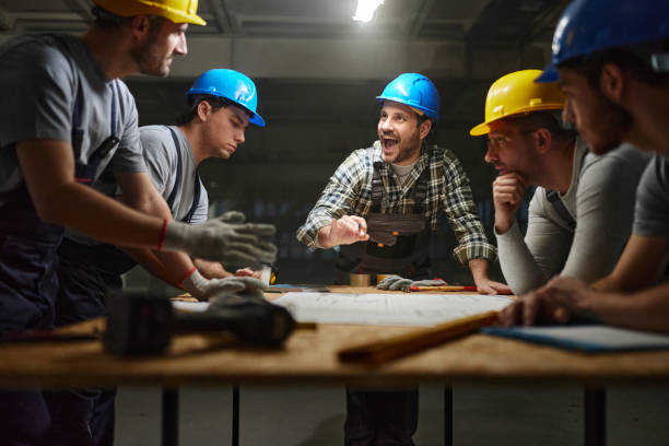 istock Happy manual worker talking about plans with his colleagues at construction site. 2201634862
