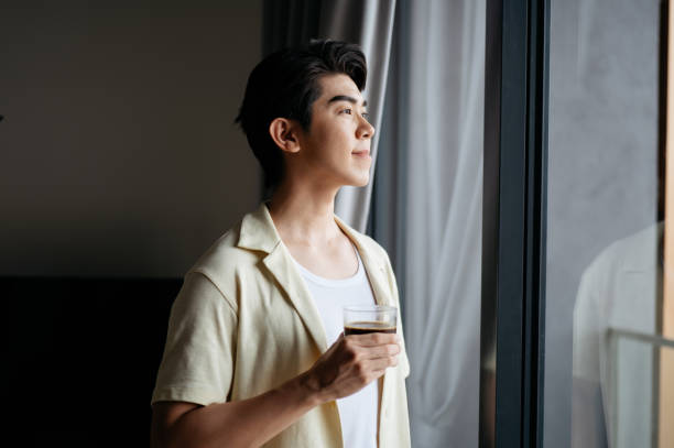 istock Asian young man enjoying coffee in the house. 2201635403
