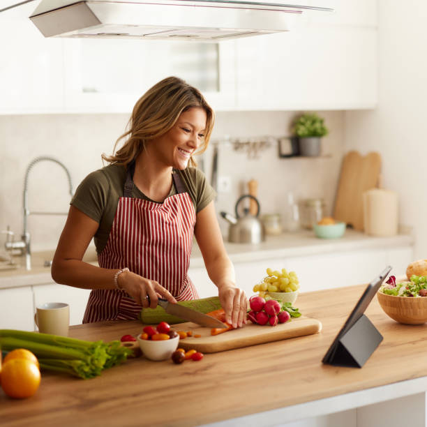 istock Happy woman reading online recipe on touchpad in the kitchen. 2201637249