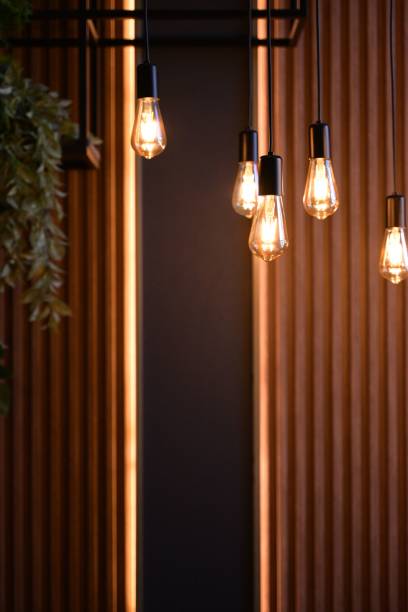 istock Warm modern hanging bulbs with wooden backdrop. 2201639586