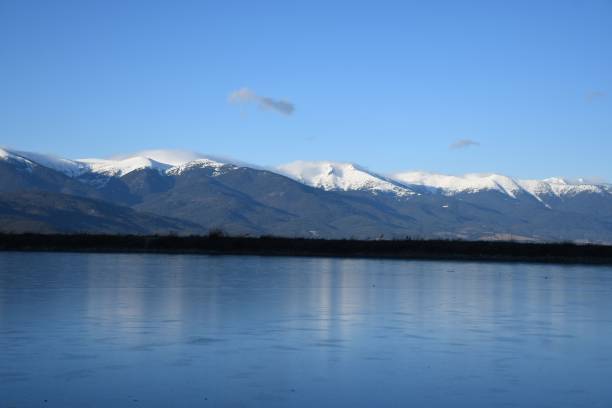 istock Snow-capped mountains reflected in a serene lake. 2201644330