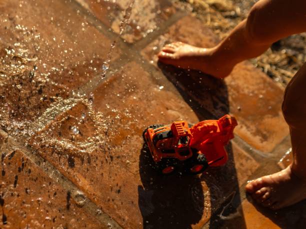 Toddler playing with water and toy truck on sunny patio
