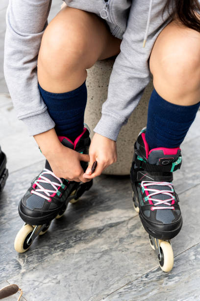 istock Young woman fastening inline skates, getting ready for urban ride 2201650234