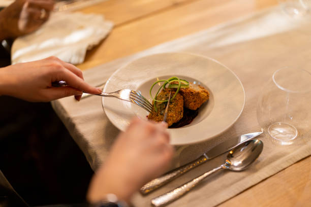 Close-up of man eating pasta while having dinner with his girlfriend in dining room.