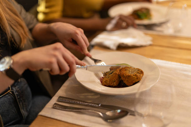 Close-up shot of unrecognizable multiracial female friends dinning in luxury restaurant