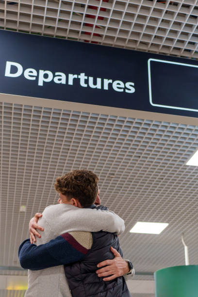 Father and son embracing warmly at the airport, sharing an emotional farewell moment filled with love and the promise of future reunions