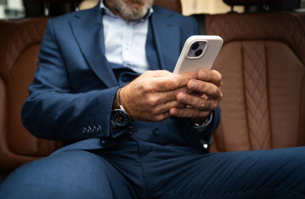 istock Senior businessman using smartphone in car 2201653683