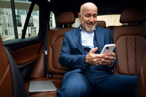 istock Senior businessman using smartphone in car 2201653717