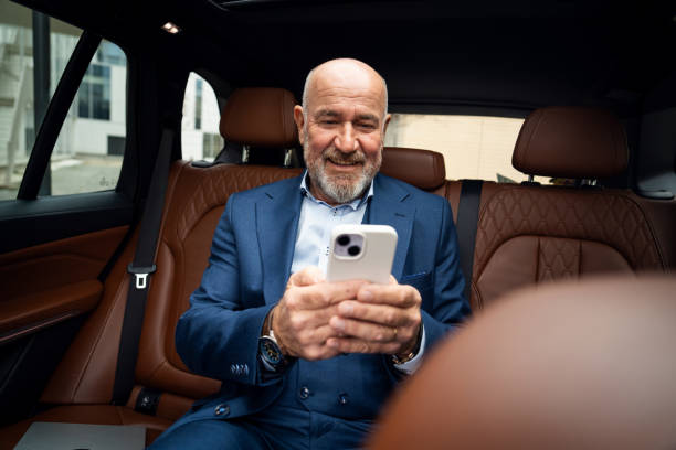 istock Senior businessman using smartphone in car 2201653725