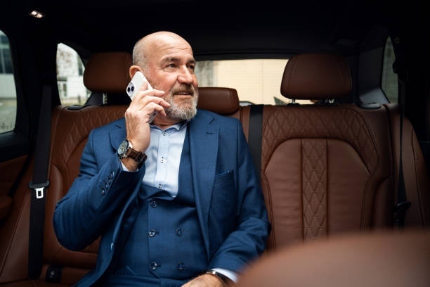 istock Senior businessman using a mobile phone in taxi 2201653729