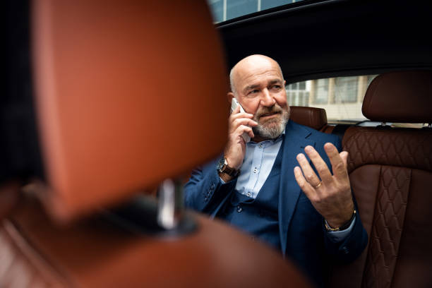 istock Senior businessman talking on smart phone while sitting in the car 2201653736