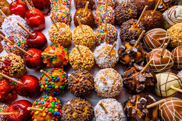 Various types of taffy apples on display of candy shop