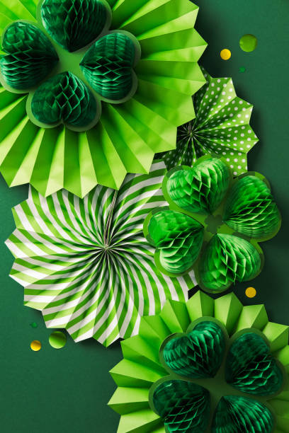 istock Happy St. Patrick's Day concept. Flat lay composition with decorative paper fans, honeycomb clover and confetti on dark green background 2201661323