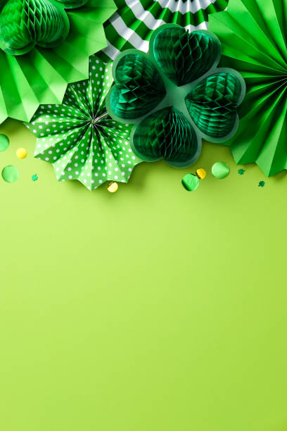 istock Happy St. Patrick's Day concept. Flat lay composition with festive decorations, paper fans, honeycomb clover leaves on bright green vertical background 2201661375