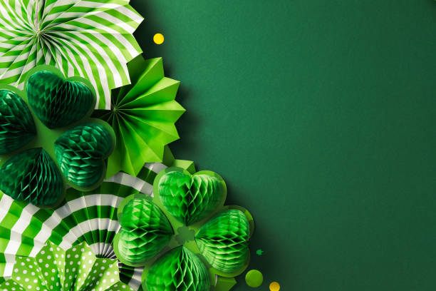 istock Happy St. Patrick's Day concept. Flat lay composition with Patrick's Day decorations, paper fans, honeycomb clover leaves, confetti on dark green background. 2201661768