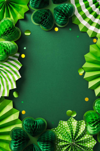 istock Happy St. Patrick's Day frame. Flat lay composition with decorative paper fans, honeycomb clover leaves, gold confetti on dark green background 2201661915