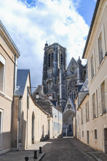 From one of the streets you can see the tower of the Cathedral of Bourges (France) on a bright day with blue sky and white clouds.