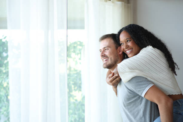 istock Happy interracial couple joking looking through a window 2201667299