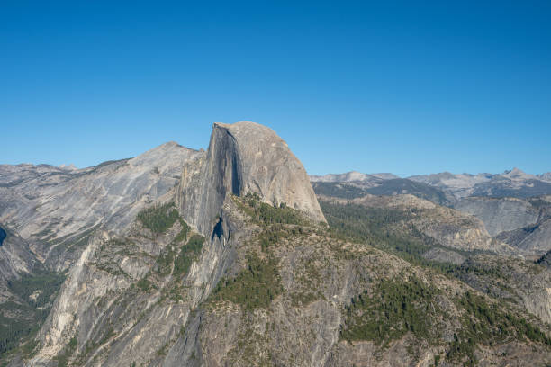 Aerial view of Half Dome seen from Glacier Point in Yosemite National Park, California, showcasing its iconic granite formation and the vast Sierra Nevada wilderness. This stunning landmark is a favorite among hikers, climbers, and nature enthusiasts.