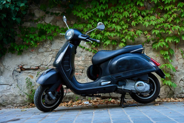 istock Black scooter parked against an old brick wall 2201670070