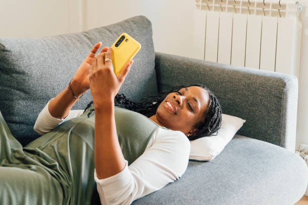 istock Cheerful woman browsing smartphone, relaxing on plush sofa within cozy home living space, enjoying digital connection 2201670690