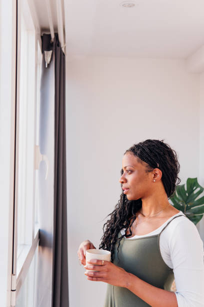 istock Woman drinking steaming coffee, contemplating near window, soft natural light creating serene indoor atmosphere 2201670755