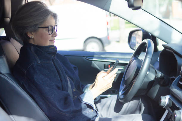 istock Mature businesswoman using smartphone while driving her car 2201671206