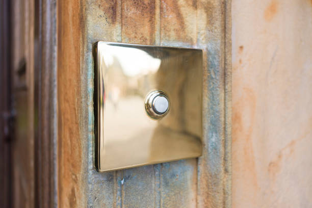 Vintage polished brass doorbell outside a front door, UK