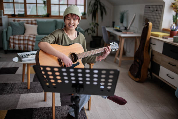 istock Passionate Female Musician Practicing Guitar in Living Room 2201674060