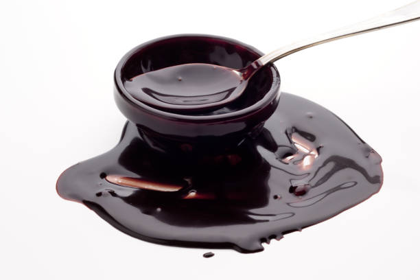 istock Delicious dark sauce in a bowl with a spoon resting on spilled sauce on a white surface 2201675917