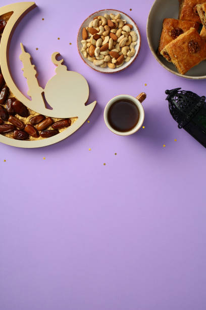 istock Ramadan flat lay featuring a crescent moon tray filled with dates, a bowl of mixed nuts, pastries, coffee, and a lantern on a purple background with star confetti 2201677694