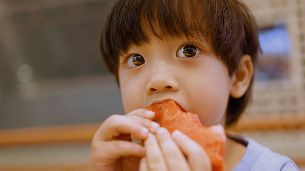 Asian boy enjoy eating water melon and food in the restaurant. 4k.