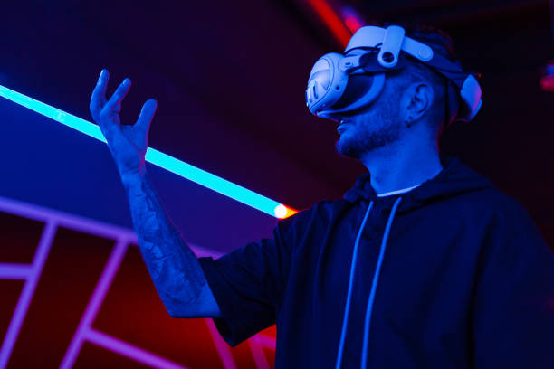 istock Amazing technology, online game, entertainment, study and virtual world in 3D simulation. Serious millennial man in vr glasses plays and tries to touch something with neon light 2201681312