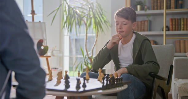 istock Thoughtful Caucasian Grandfather and Grandson Playing Chess 2201682382