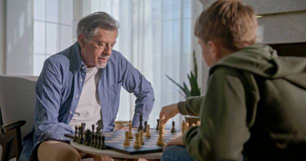 istock Elderly Man and Boy Engaged in Chess Match 2201682387