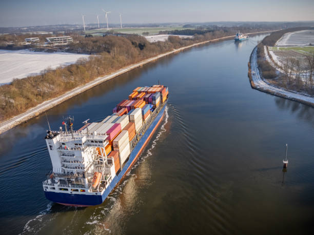 istock Container ship navigating through the Kiel Canal in winter conditions. Vessel, loaded with shipping containers, moves through the waterway. 2201683637
